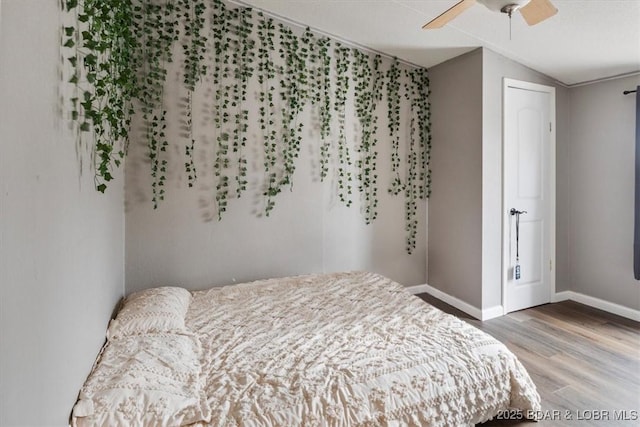 bedroom featuring lofted ceiling, wood finished floors, a ceiling fan, and baseboards