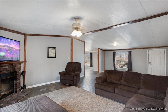 living area with baseboards, a fireplace, ornamental molding, and dark wood-type flooring