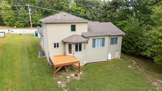 rear view of house featuring roof with shingles, a yard, and central AC unit