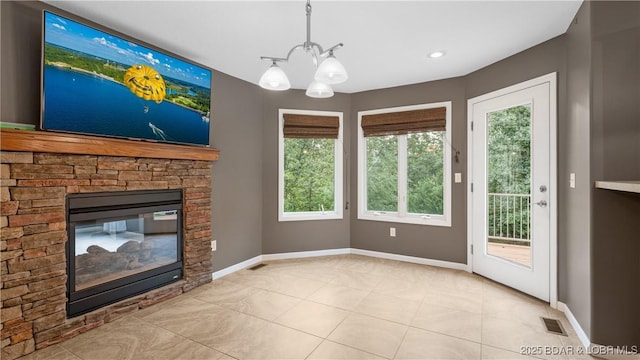 unfurnished living room featuring an inviting chandelier, a fireplace, visible vents, and baseboards