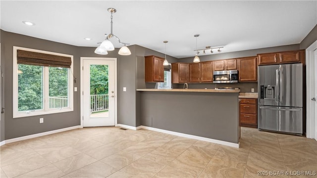 kitchen with brown cabinets, stainless steel appliances, light countertops, and decorative light fixtures