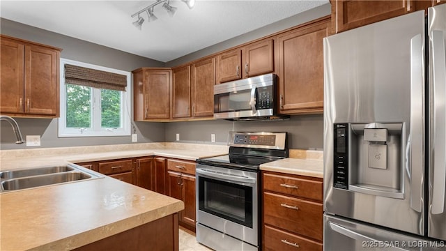 kitchen featuring brown cabinetry, appliances with stainless steel finishes, light countertops, and a sink