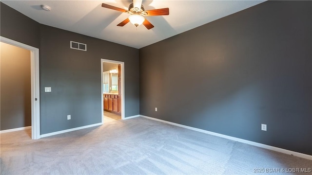 spare room featuring a ceiling fan, light colored carpet, visible vents, and baseboards