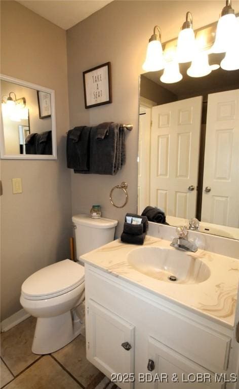 half bath featuring vanity, tile patterned flooring, and toilet