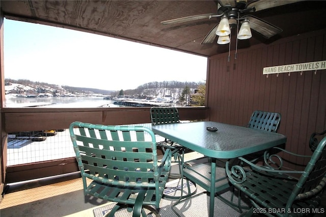 snow covered back of property with a ceiling fan and outdoor dining space