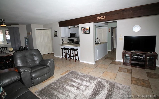 living room featuring ceiling fan, baseboards, and light tile patterned floors