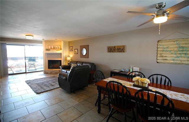 dining area featuring a fireplace, a ceiling fan, and light tile patterned flooring