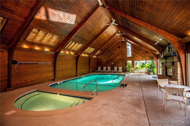 pool with an outdoor stone fireplace and a patio