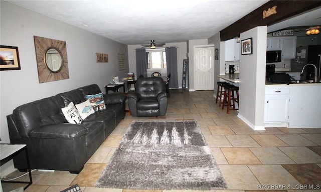 living room with light tile patterned floors, a ceiling fan, and baseboards