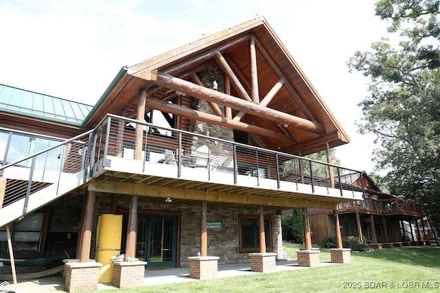 rear view of house with metal roof, a standing seam roof, stone siding, and a lawn