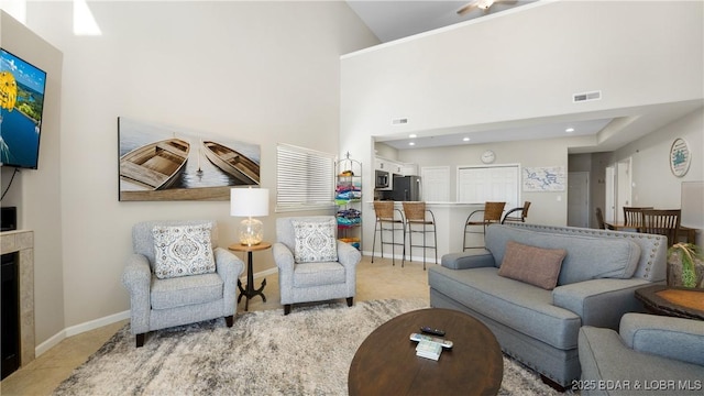 living room featuring recessed lighting, visible vents, a high ceiling, a high end fireplace, and baseboards