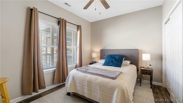 bedroom with a ceiling fan, light wood-type flooring, visible vents, and baseboards