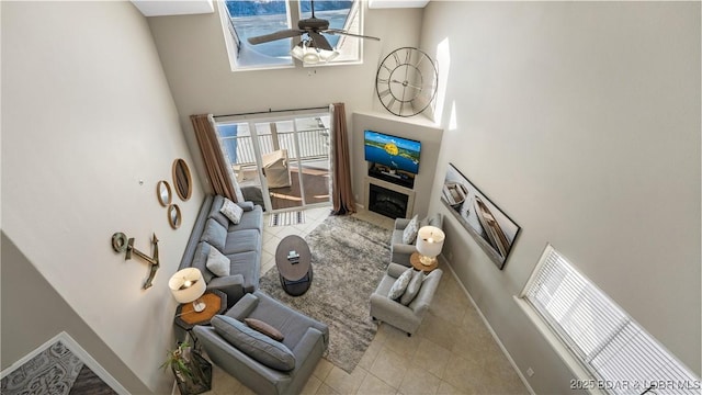 living room with a towering ceiling, ceiling fan, and baseboards