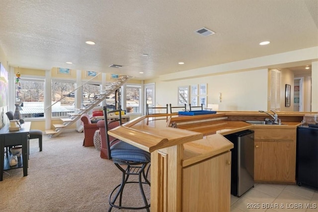 kitchen featuring visible vents, a sink, a textured ceiling, stainless steel dishwasher, and recessed lighting