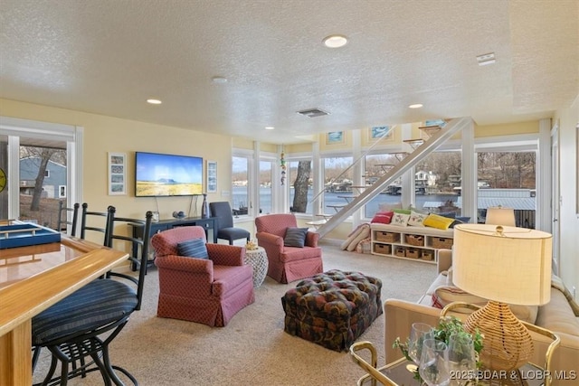 carpeted living area featuring stairs, a textured ceiling, visible vents, and recessed lighting