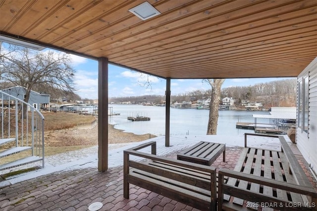 snow covered patio featuring a water view