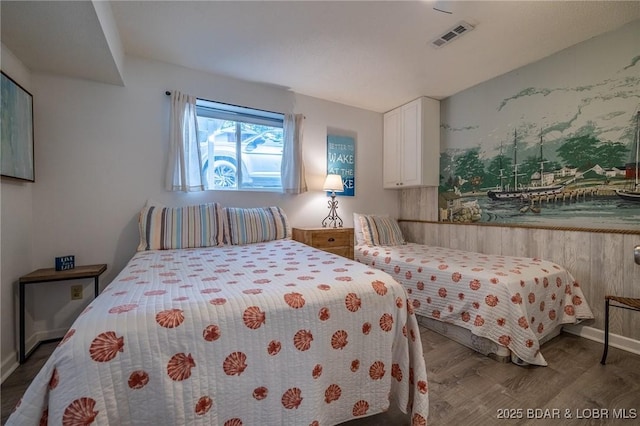 bedroom featuring baseboards, visible vents, and wood finished floors