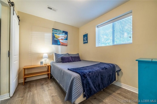 bedroom with wood finished floors, visible vents, and baseboards