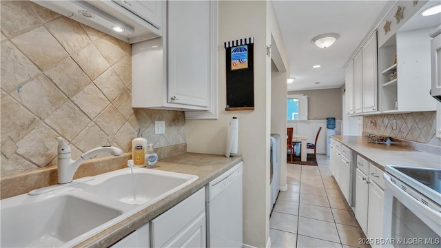 kitchen featuring light tile patterned floors, white appliances, a sink, white cabinets, and light countertops