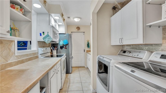 clothes washing area featuring light tile patterned floors, laundry area, separate washer and dryer, and visible vents