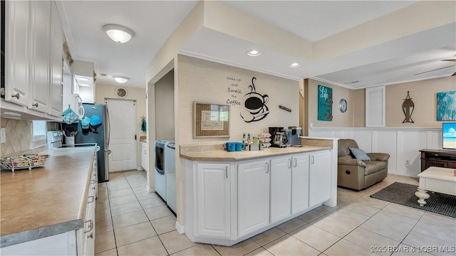 kitchen featuring light tile patterned floors, light countertops, open floor plan, white cabinets, and wainscoting