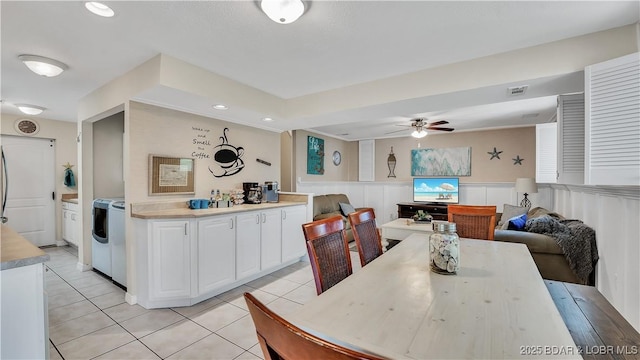 dining room with washer / dryer, visible vents, a ceiling fan, a wainscoted wall, and light tile patterned flooring