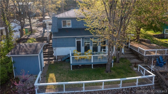 back of property featuring roof with shingles, a yard, a storage unit, fence, and an outdoor structure