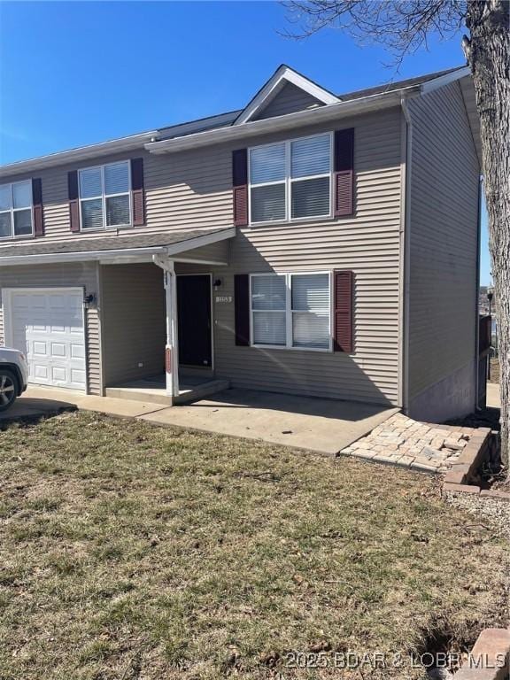 view of front of property with a patio, an attached garage, and a front yard