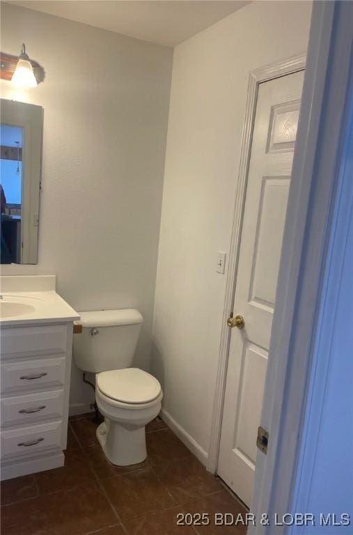 bathroom featuring toilet, tile patterned floors, baseboards, and vanity