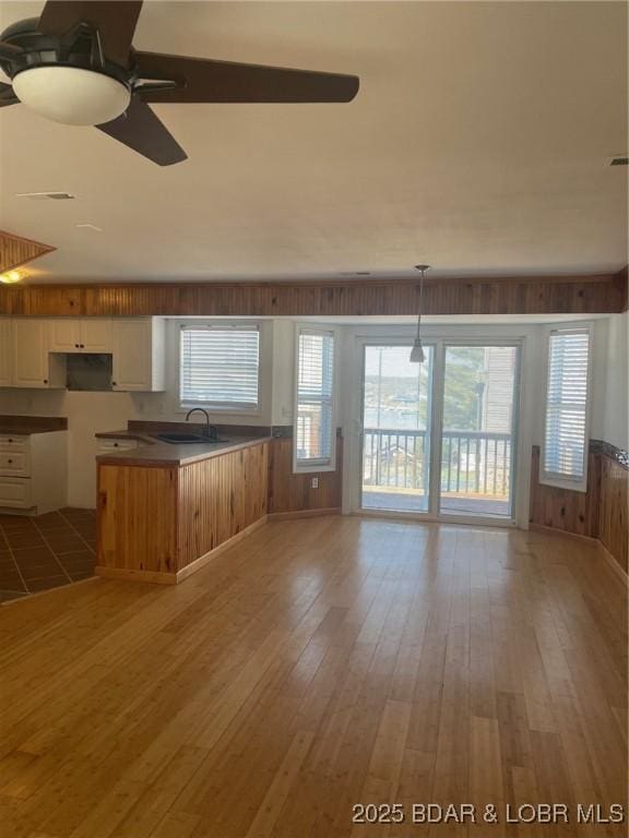 1153 Cedar Dr, Osage Beach, MO 65065 - kitchen featuring a ceiling fan, wooden walls, light wood-type flooring, white cabinets, and a sink
