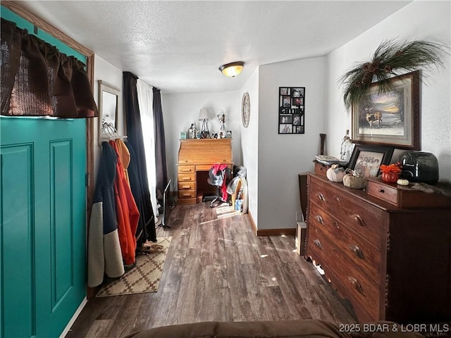 interior space with a textured ceiling, baseboards, and dark wood-type flooring