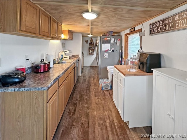 kitchen with dark wood-type flooring, wood counters, wood ceiling, a sink, and freestanding refrigerator