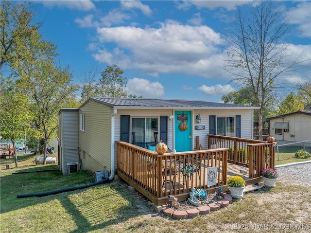 view of front of home with metal roof, a wooden deck, and a front lawn