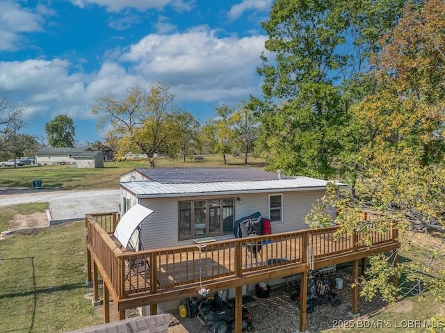 back of house featuring metal roof, a lawn, and a wooden deck