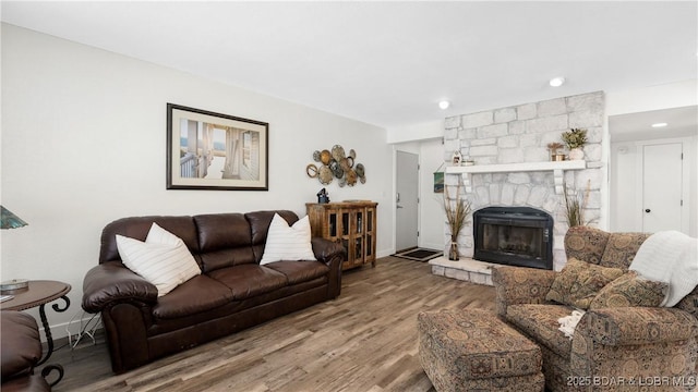 living room with recessed lighting, a stone fireplace, baseboards, and wood finished floors