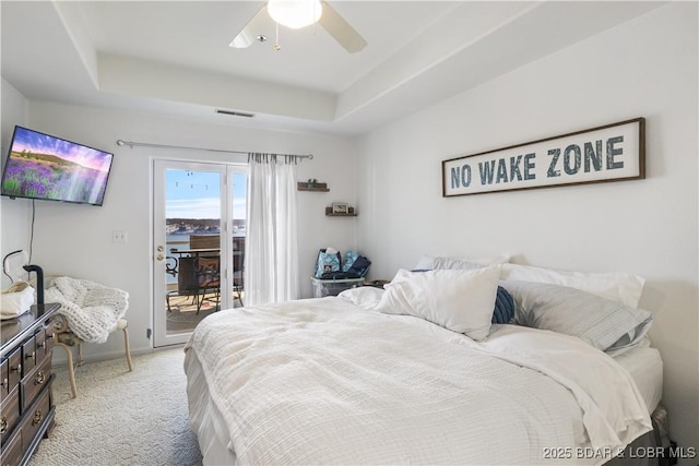 bedroom featuring light carpet, visible vents, a raised ceiling, ceiling fan, and access to outside