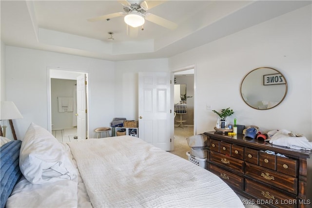 bedroom featuring ensuite bathroom, a raised ceiling, and a ceiling fan