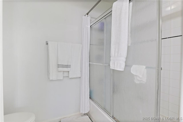 bathroom featuring toilet, baseboards, and bath / shower combo with glass door