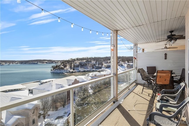 snow covered back of property featuring a ceiling fan and a water view