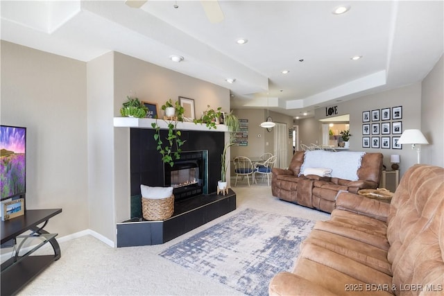 carpeted living area with a fireplace, baseboards, a tray ceiling, and recessed lighting