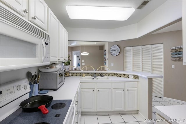 kitchen with white appliances, decorative light fixtures, a peninsula, and white cabinetry