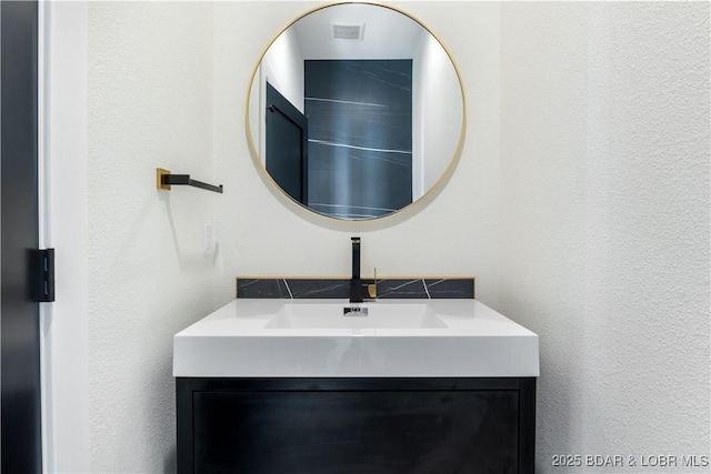 bathroom with a textured wall, vanity, and visible vents