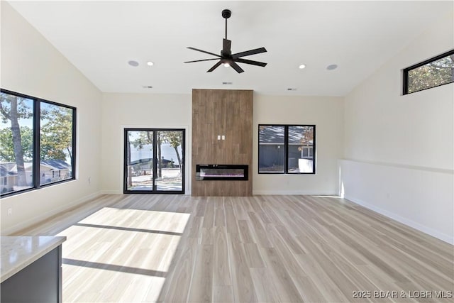 unfurnished living room with ceiling fan, recessed lighting, a large fireplace, baseboards, and light wood-style floors