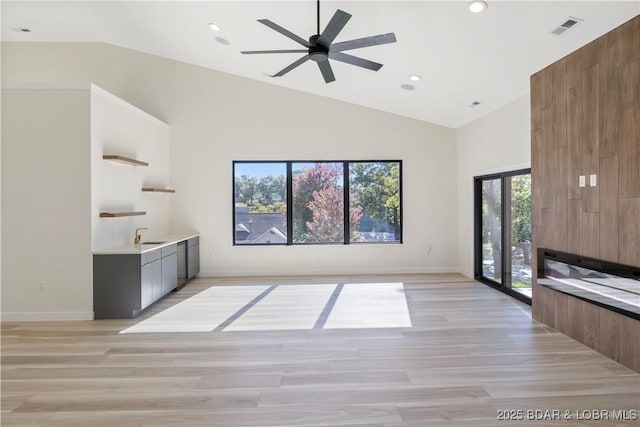 unfurnished living room featuring light wood-type flooring, high vaulted ceiling, and visible vents