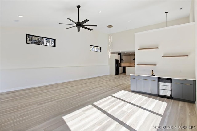 unfurnished living room with light wood-type flooring, ceiling fan, baseboards, and recessed lighting