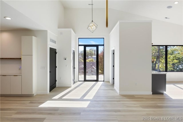 entrance foyer featuring recessed lighting, visible vents, baseboards, a towering ceiling, and light wood-style floors