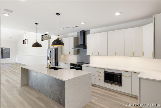 kitchen with wall chimney range hood, a kitchen island with sink, built in microwave, and white cabinets