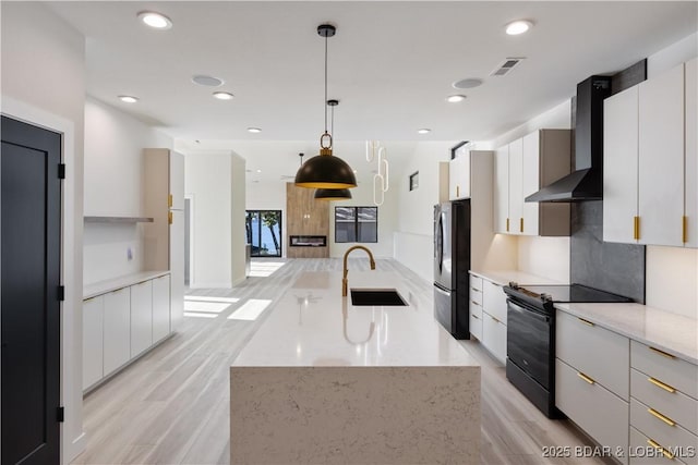 kitchen featuring decorative light fixtures, freestanding refrigerator, white cabinets, black range with electric cooktop, and wall chimney exhaust hood