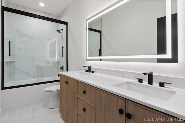 bathroom featuring toilet, marble finish floor, enclosed tub / shower combo, and a sink