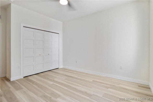 unfurnished bedroom with baseboards, ceiling fan, a closet, and light wood-style floors